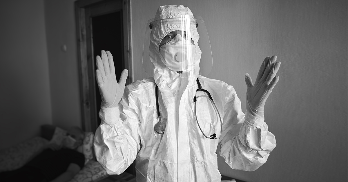 Black and white image of doctor in PPE suit, respirator, gloves, with phonendoscope, visiting patient at home during covid-19 quarantine, after disinfecting hands getting ready for examination