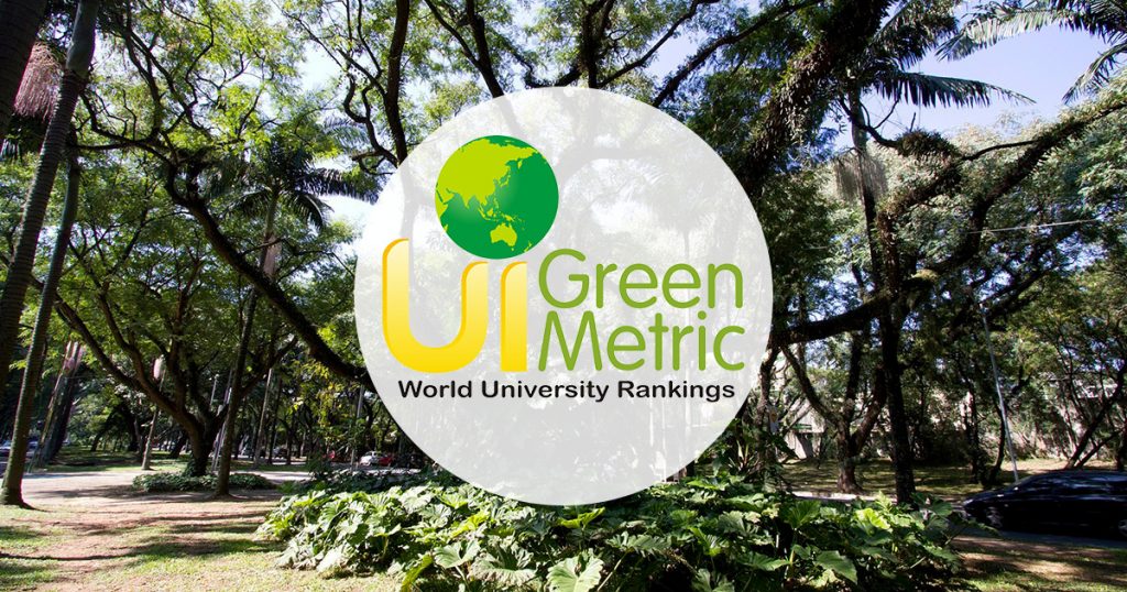 Na imagem tem uma área verde ao fundo, com árvores e em primeiro plano um selo com a inscrição UI GreenMetric World University Rankings