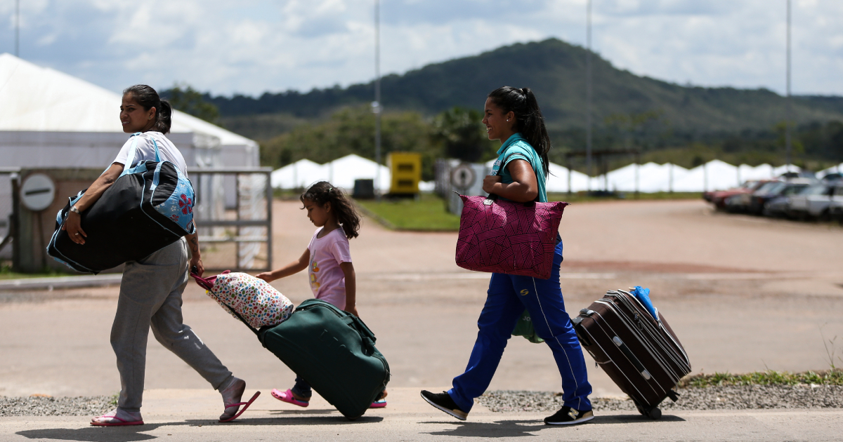 Imagem de imigrantes (três ao todo, duas mulheres adultas e uma menina) venezuelanos carregando suas respectivas bagagens