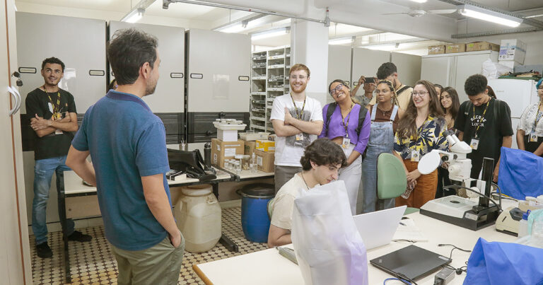 Vários estudantes numa sala do Museu de Zoologia da USP, com uma pessoa falando e os outros prestando atenção