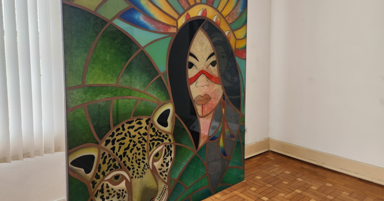 Mosaico de vidros pintados mostrando mulher indígena, onça pintada e vegetação ao redor.