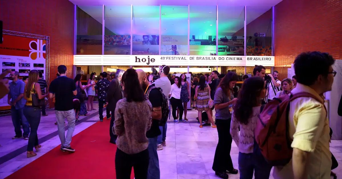 Varias pessoas na entrada de cinema, no qual tem uma mensagem em luminoso no alto: "Hoje, Festival de Brasilia, do cinema brasileiro"