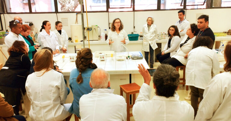 Professor num laboratório de química dando aula para professores de química do ensino básico em ação de extensão universitária