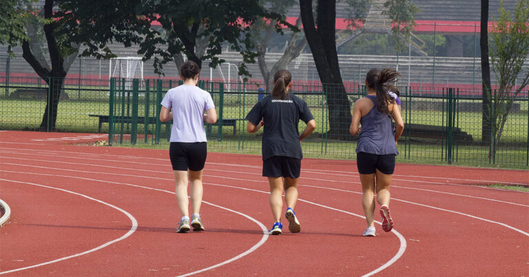 Três pessoas correndo em pista de atletismo