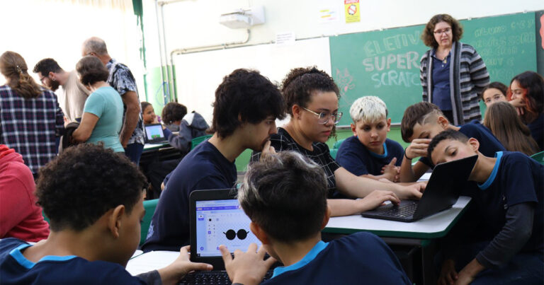 Estudantes em sala de aula mexendo em computadores portáteis