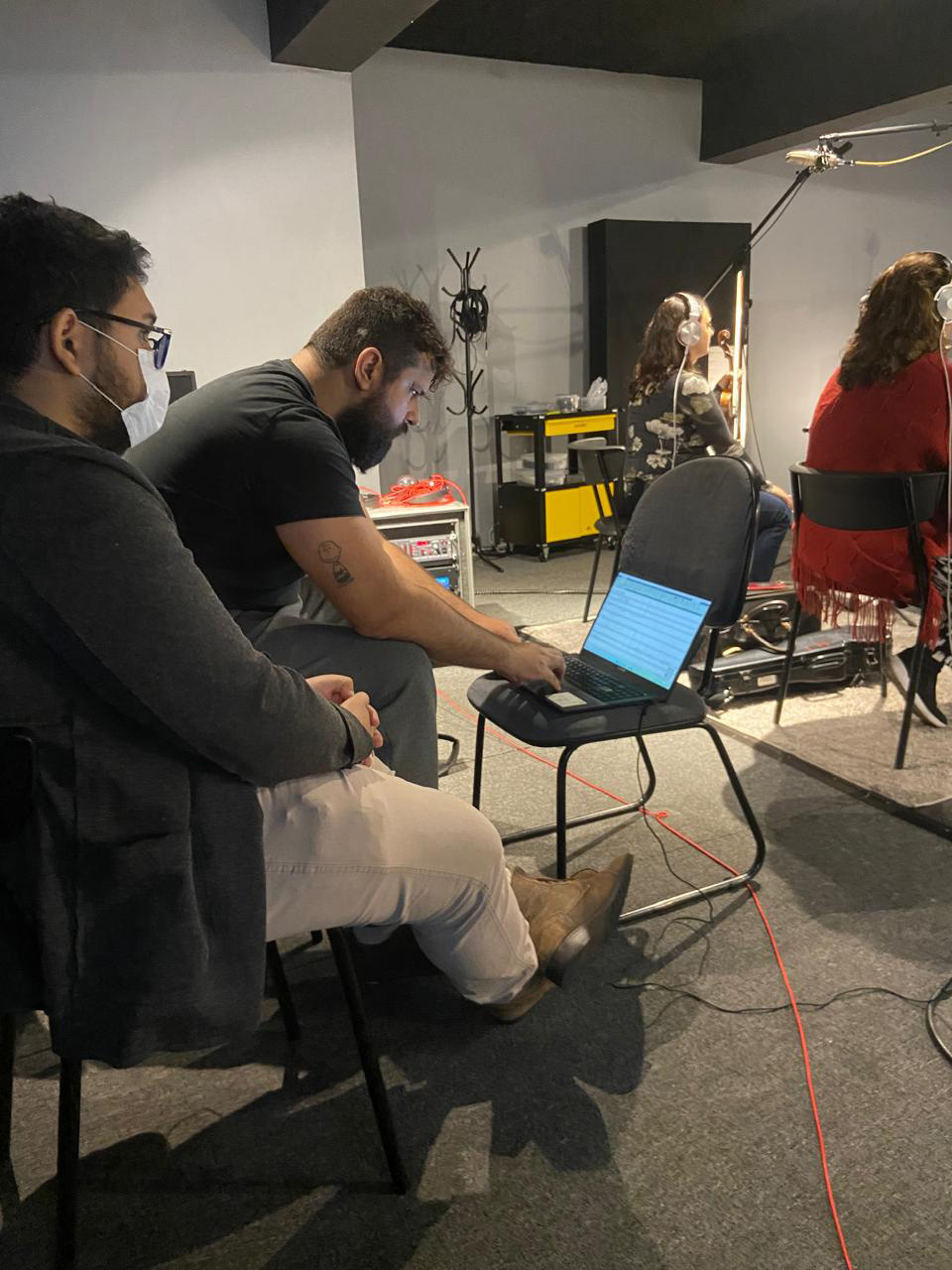 Homem digitando num computador que está apoiado numa cadeira.