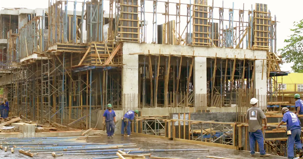 Profissionais de uma construtora em um terreno com um prédio sendo construído