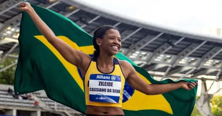 Mulher negra atleta, com camiseta branca e com a bandeira do Brasil nas costas