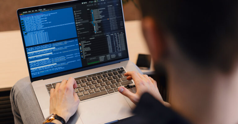 Homem de costas olhando para a tela de um notebook fazendo programação