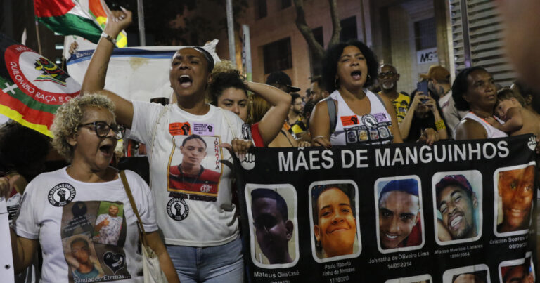 mulheres em sua mairia negras segurando cartazes com fotos de seu filhos que foram mortos em operações policiais na comunidade e manguinhos no rio de janeiro