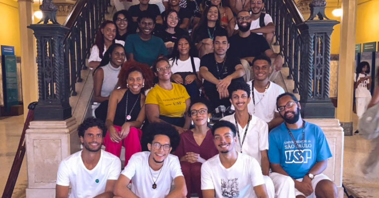 Imagem: Grupo de estudantes negros sentados em uma das escadarias da Faculdade de Medicina da USP