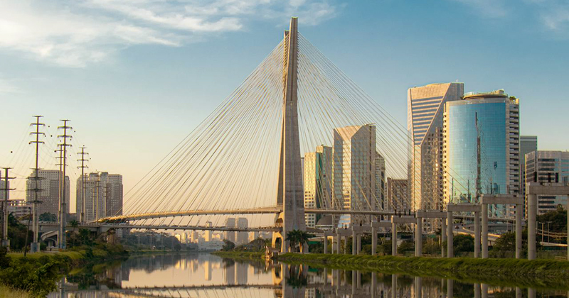 Ponte estaiada sobre um rio ao centro e com prédios nas laterais