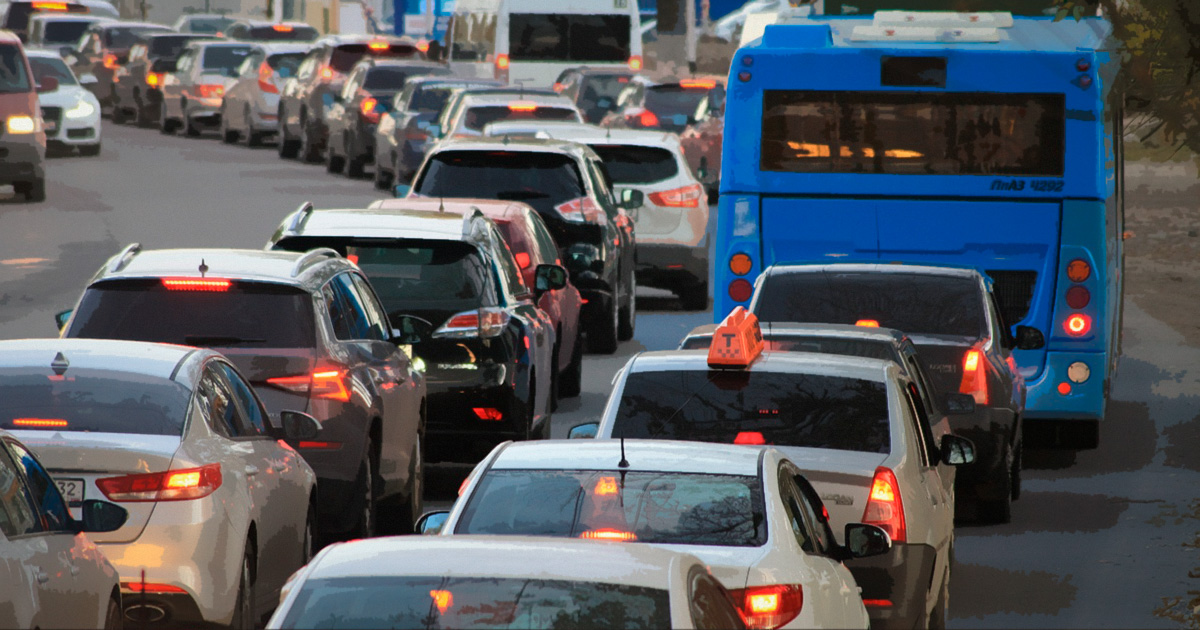 Imagem de um trânsito congestionado numa grande avenida, com carros e ônibus enfileirados e parados