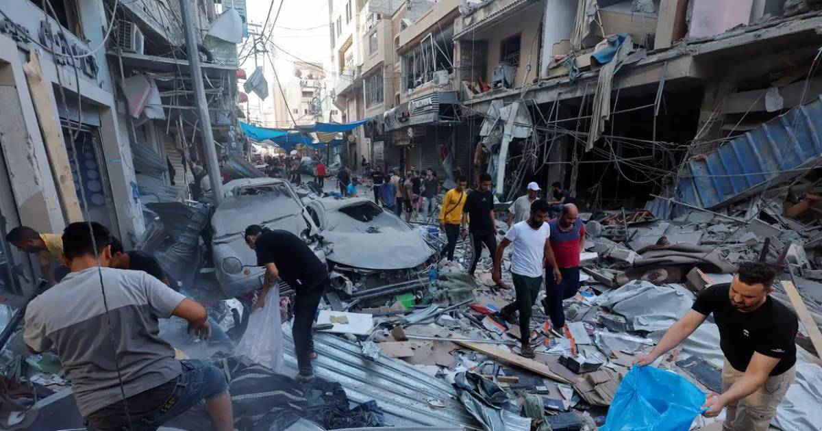 A imagem mostra um cenário de uma rua com prédios e carros destruídos após bombardeios