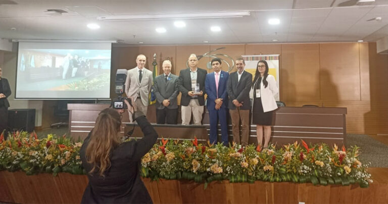 Seis pessoas em cima de um palco com um deles segurando um troféu