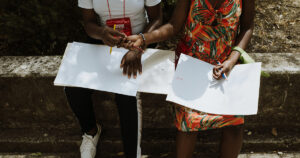 Imagem: Mãos negras com lápis nas mãos sobre folhas brancas