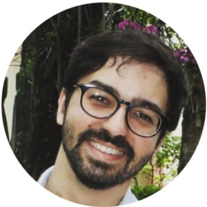 Jovem branco, barba e bigode, usando óculos e sorrindo