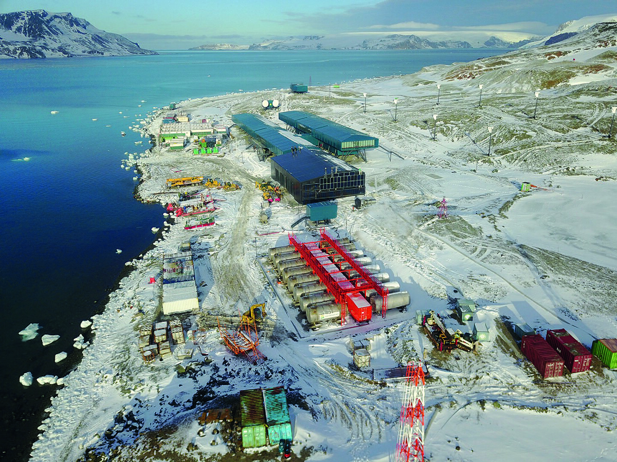 Imagem aérea de estruturas como prédios, plataformas e containers sobre o gelo, circundadas pelo mar