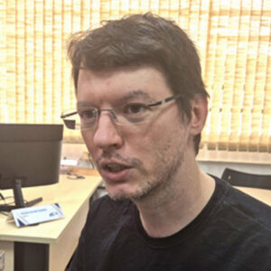 Foto do professor Herbert João, um homem branco, de cabelo castanho e curto, com um óculos quadrado. Na imagem, ele está falando.