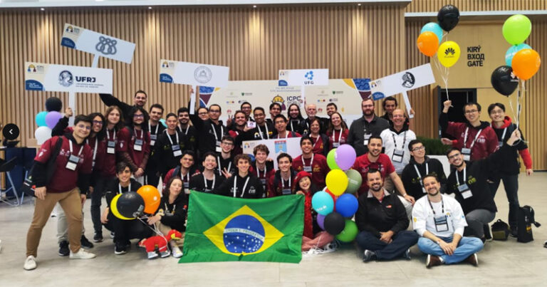 Vários estudantes reunidos para fotos sendo alguns em pé e outros sentados com alguns segurando uma bandeira do brasil