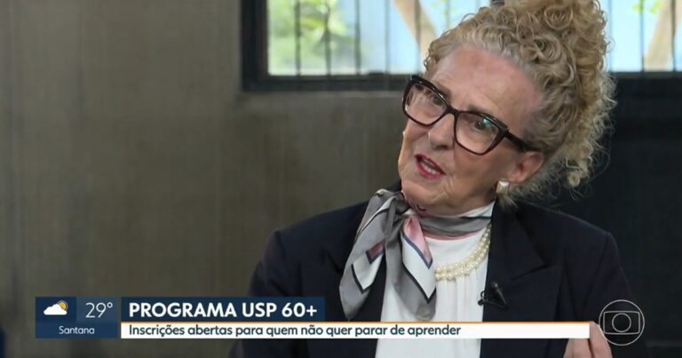 Mulher idosa, com cabelo loiro e coque, oculos de armação escura.