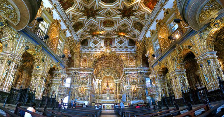 Visão do altar de uma igreja com ornamentos dourados em toda a sua estrutura