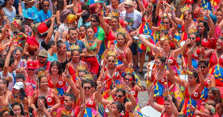 Diversos foliões vestidos em tons de vermelho curtem o carnaval na rua