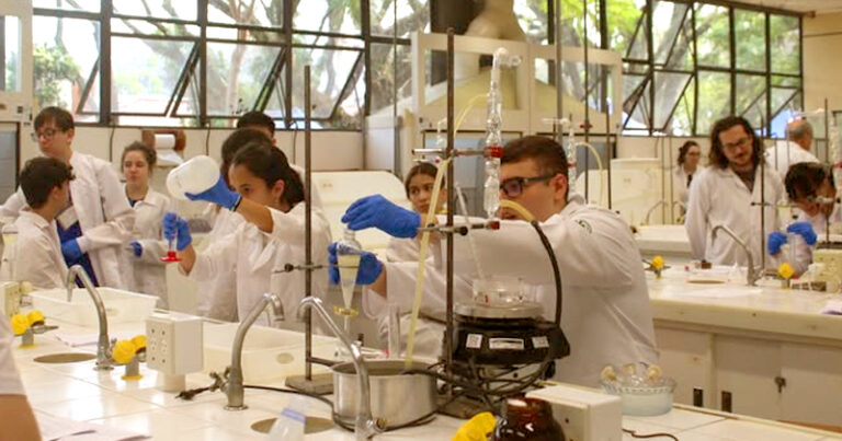 Estudantes em laboratório de química manuseando equipamentos em bancadas