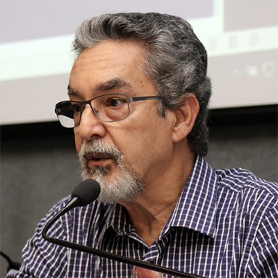 Homem de cabelos grisalhos, falando a um microfone.