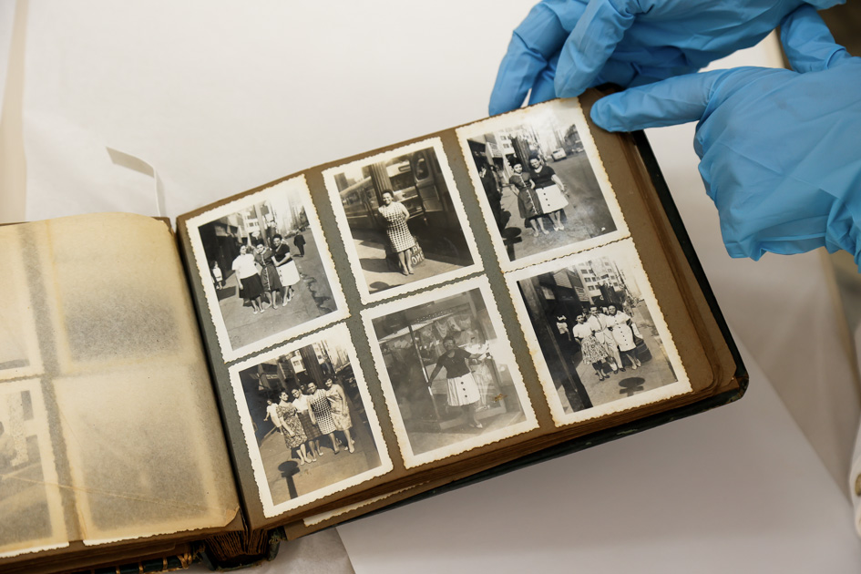 Mãos enluvadas exibem álbum de fotos antigas