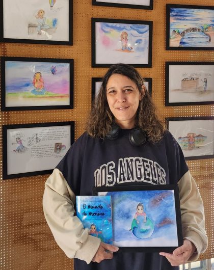 A artista Mariana Komesu com o livro que ilustrou e algumas de suas obras ao fundo - Foto: Grace Donatti